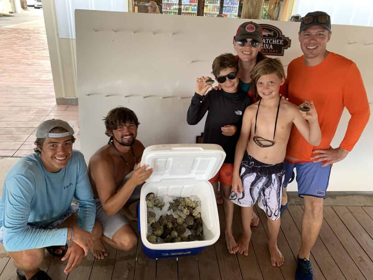 Family posing at Steinhatchee Marina with a bunch of scallops they caught with a guide.